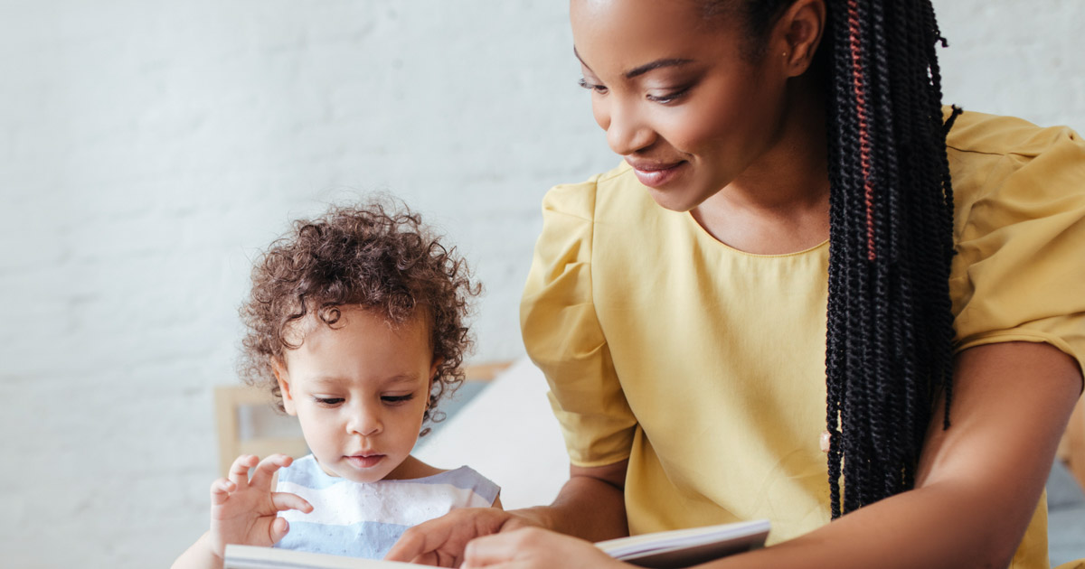 Youong woman reading a book to a baby girl.