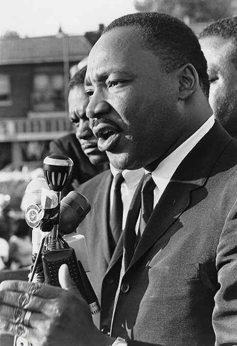 Martin Luther King, Jr. speaking at a microphone in front of a crowd.